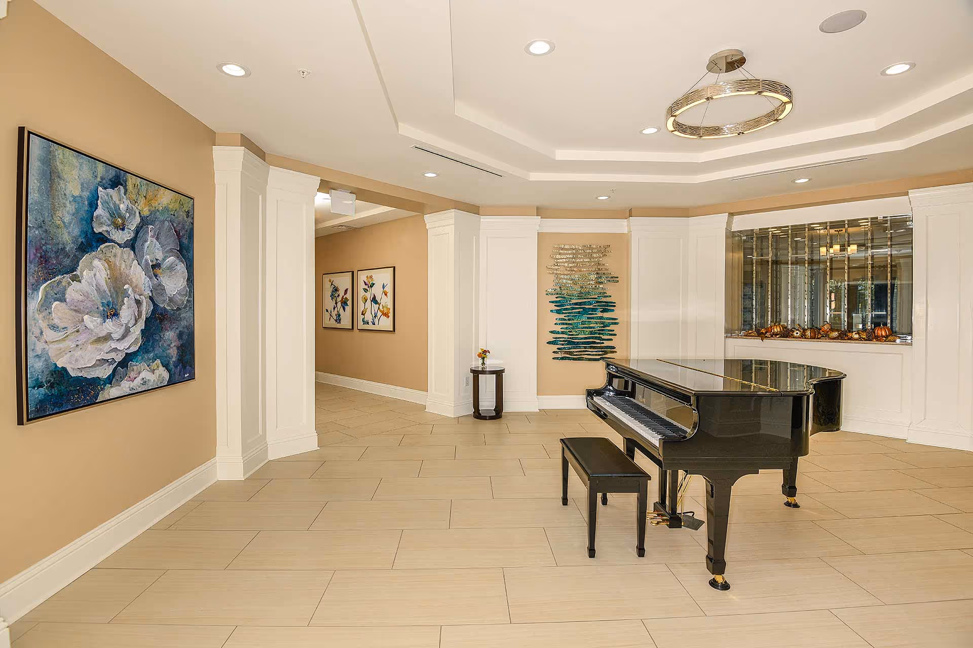 Spacious interior lobby with a black grand piano and bench, decorative wall art, columns, and recessed ceiling lighting.