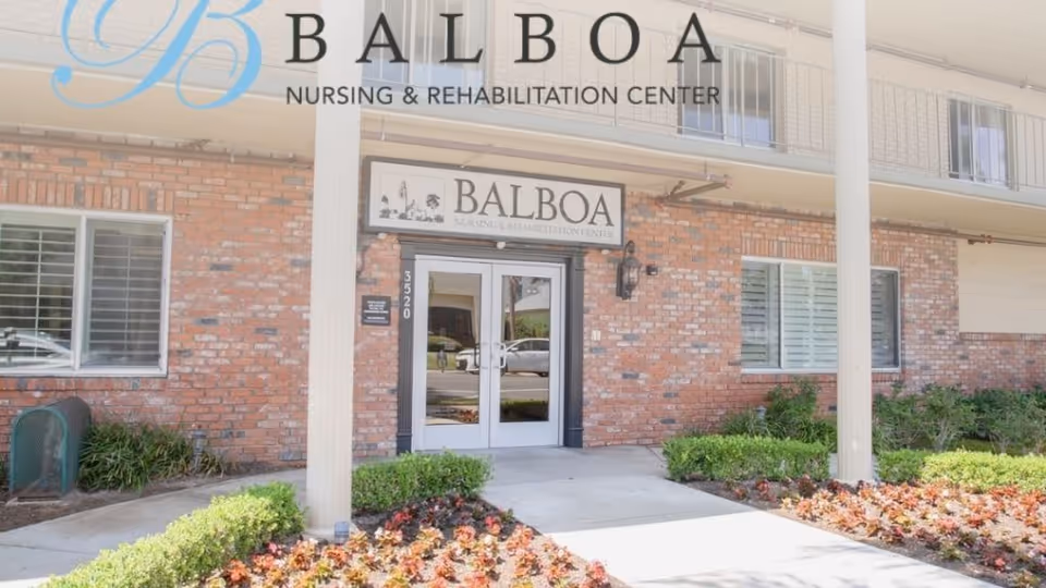 Front entrance of Balboa Nursing & Rehabilitation Center with brick facade, columns, landscaping and double glass doors.