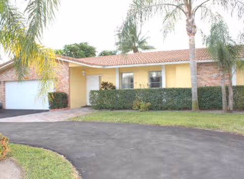 Front exterior of Bright Horizons of Ramblewood with driveway, yellow facade, and palm trees