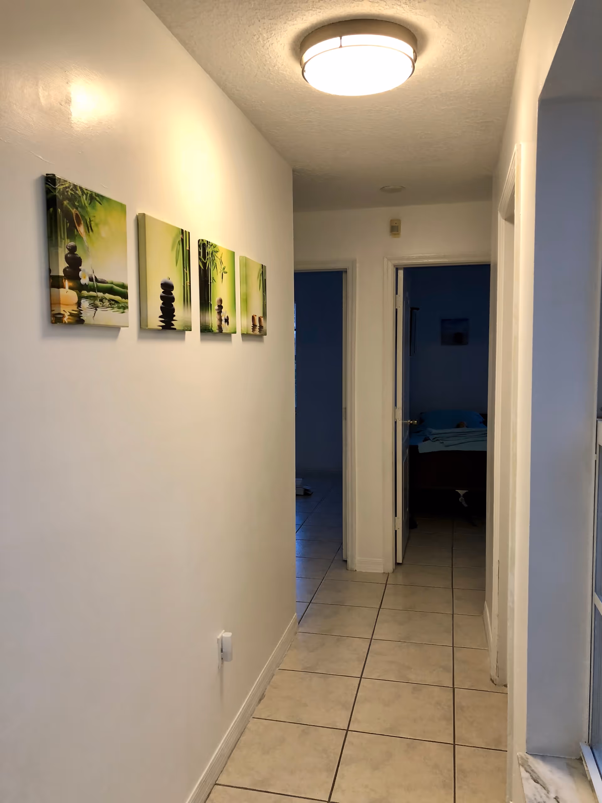 Bright white hallway in a senior living facility with tiled floor and bedroom doors