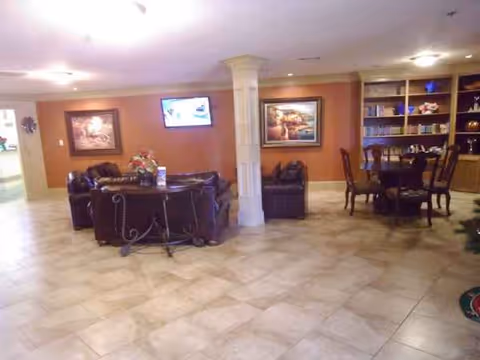 A senior living facility lobby with leather couches, a column, wall art, and a dining area.