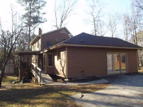 Brown single-story building with a ramp and trees, exterior view of a residential facility.