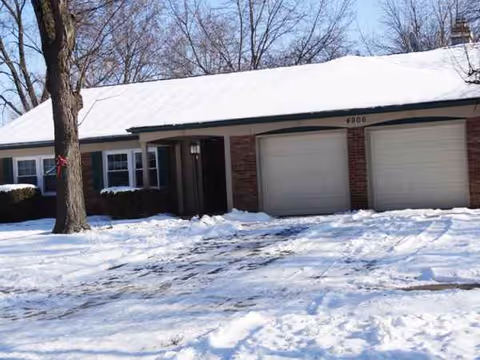 Snow-covered, single-story facility with two garage doors, a front entrance, and leafless trees.