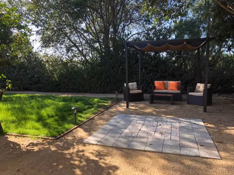 Outdoor seating area with cushioned furniture beneath a canopy on a stone patio.