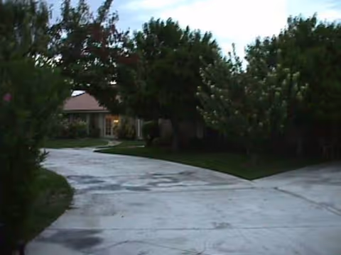 Curved concrete driveway leads to a single-story facility entrance surrounded by trees.