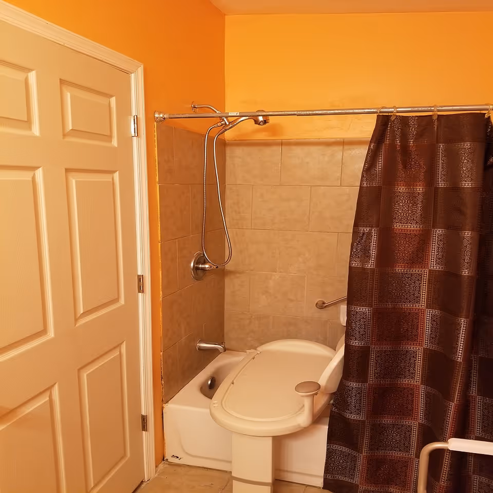 Bathroom with a shower, brown curtain, tiled walls, and a toilet.