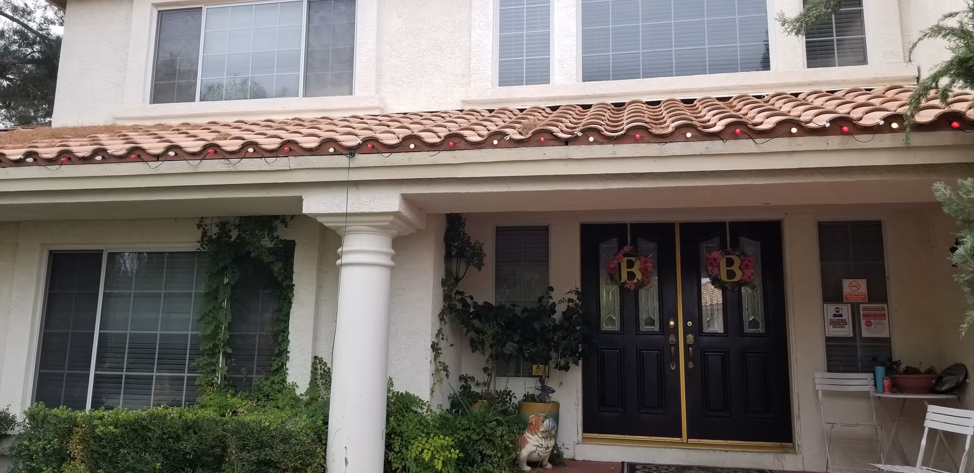 Double black doors with gold trim flank a villa-style senior living building entrance.