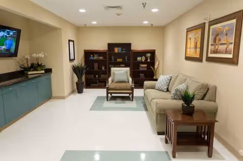 Neutral-toned lounge area with sofa, chairs, shelves, and framed wall art.