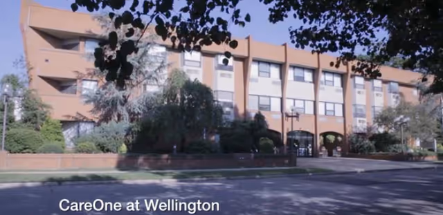 Exterior view of CareOne at Wellington building with arches, trees, and street frontage.