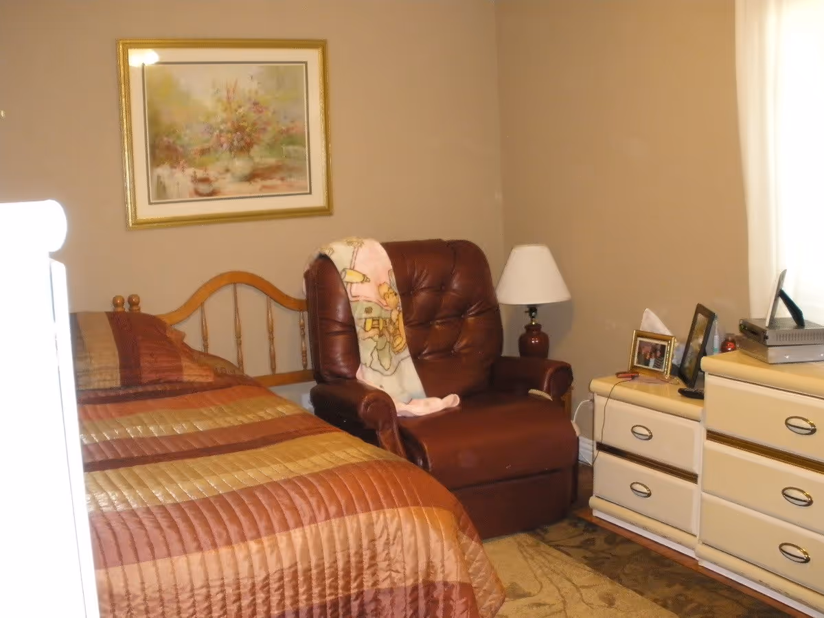 Cozy bedroom with a bed, leather recliner chair, dresser, and bedside lamp.