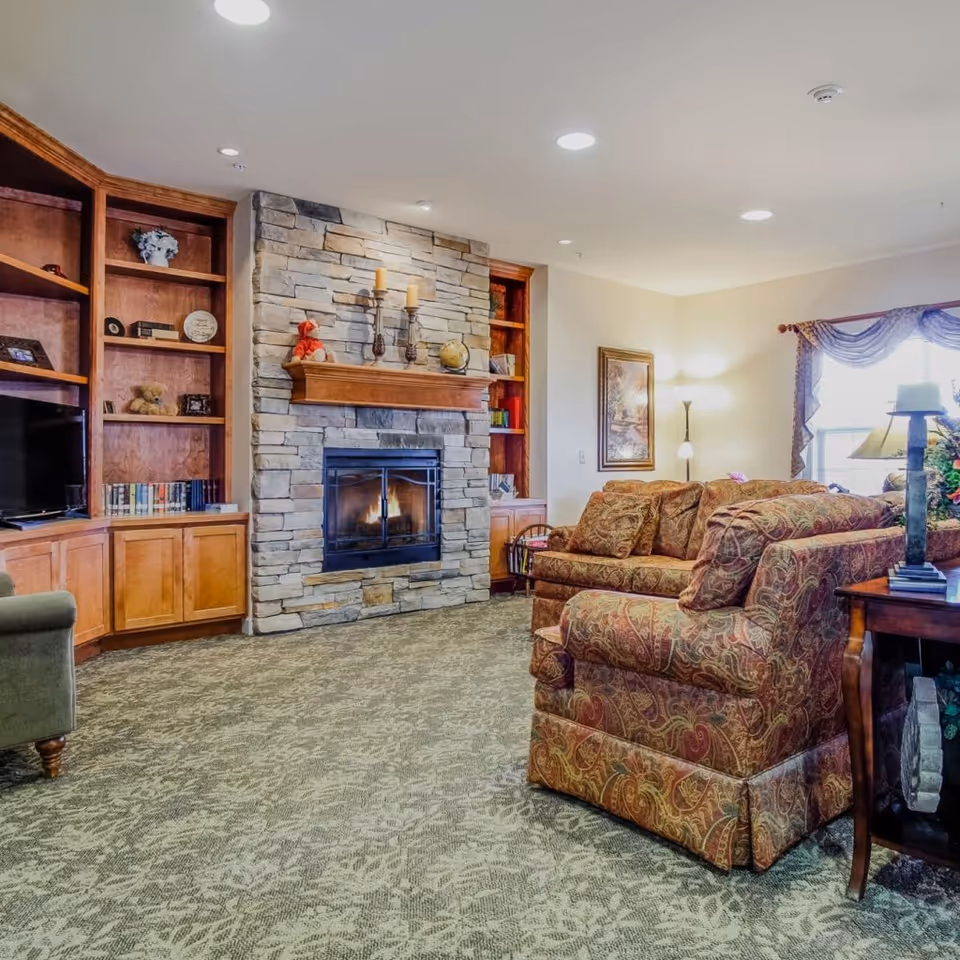 Cozy living area in a senior living facility featuring a fireplace and comfortable seating.
