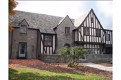 Exterior of a Tudor-style stone building with timber framing and peaked roofs.