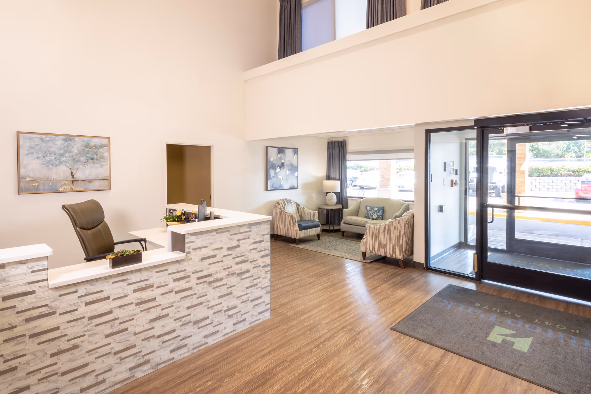 Bright reception desk and small lobby seating area next to glass entrance doors.