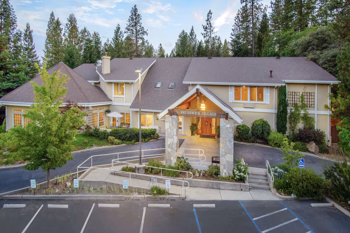 Exterior view of Brunswick Village assisted living facility with stone entry arch and parking.