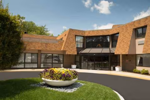 Exterior view of Bear Mountain at Reading, brick building with glass entrance and circular flower bed.