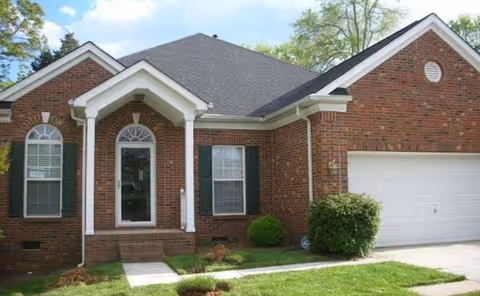 Brick single-story house with a front porch, arched entry, and attached garage.