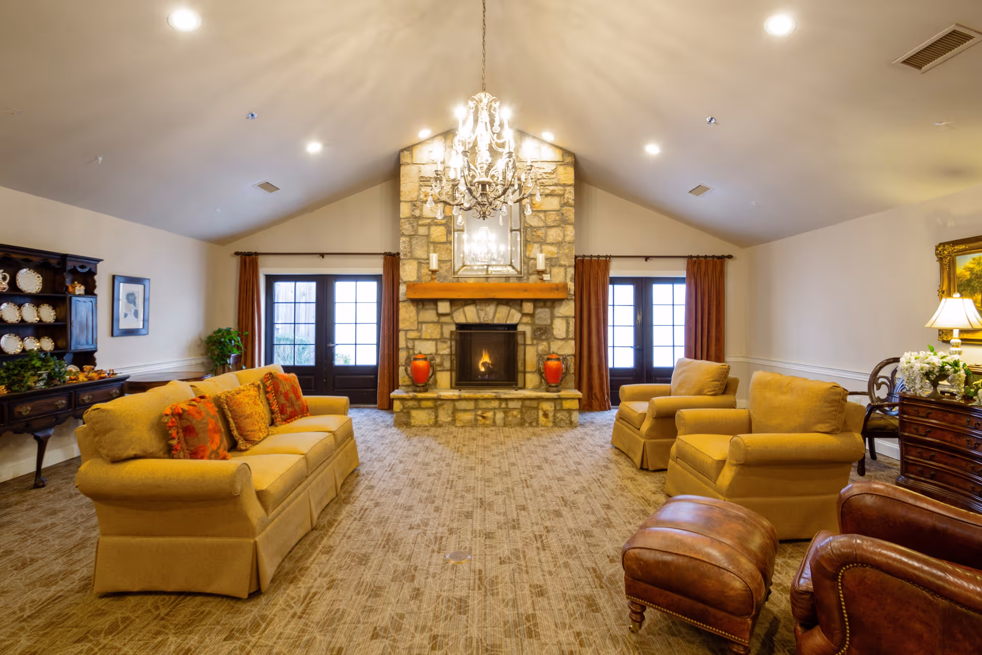 Spacious living room with a vaulted ceiling, stone fireplace, chandelier, sofas and armchairs.