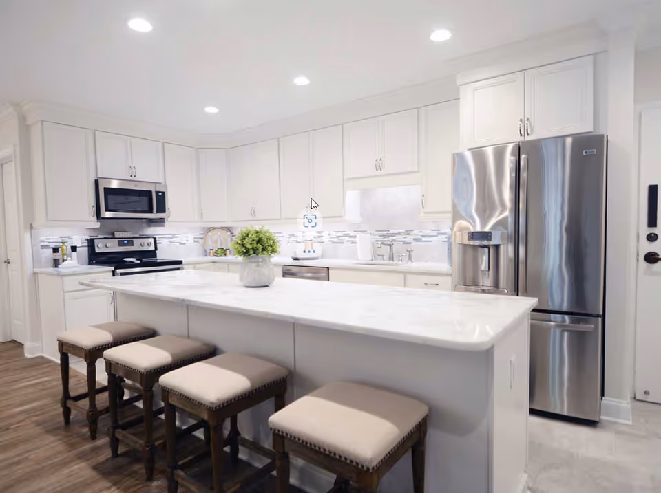 Bright modern kitchen with white cabinets, a marble island with four stools, and stainless steel appliances.