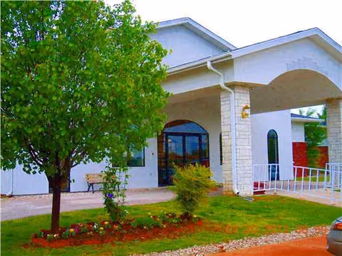 Front view of Maries Manor senior living facility with trees and bench.