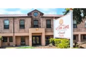 Two-story brick senior living facility front with a covered main entrance and a landscaped sign for Autumn Lake.