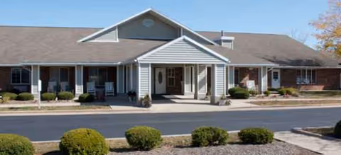 Brookdale Urbana senior living facility exterior with entrance, shrubs, and a paved street in front.