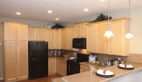 Sunlit Lakeside Crossing kitchen featuring wooden cabinets, black appliances, and an island.