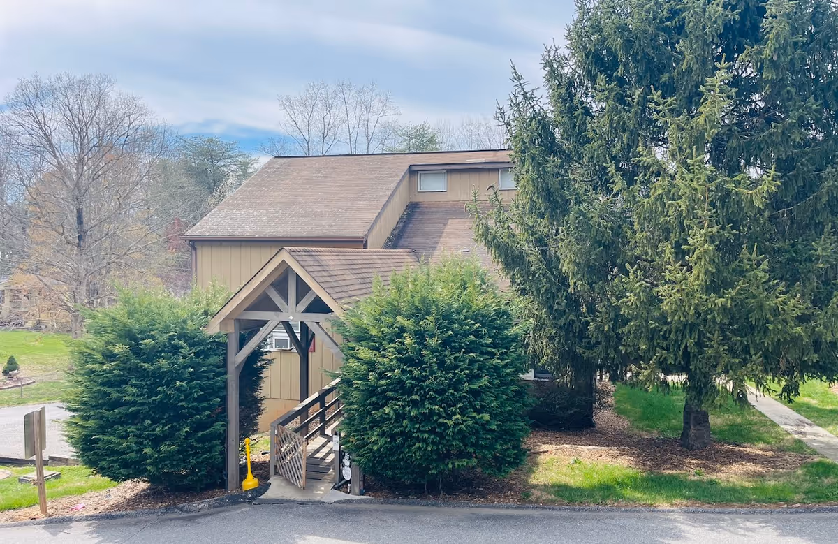 Exterior view of Burke Assisted Living entrance with a small porch and surrounding greenery.