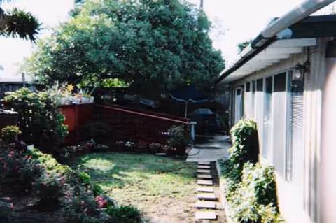 Backyard garden with stepping stones, greenery, and a single-story facility exterior.