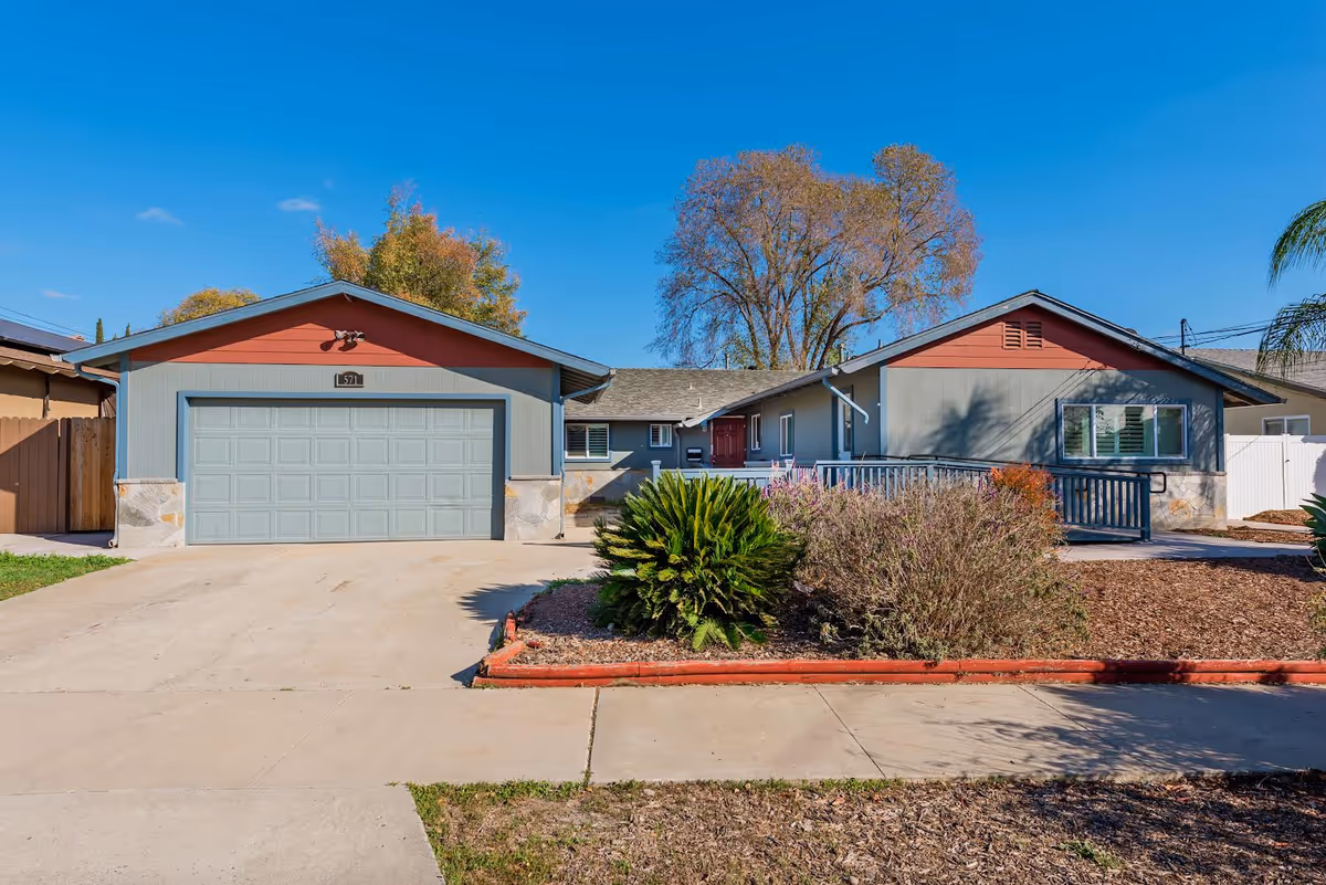 Front exterior of a single-story ranch-style house with a two-car garage, driveway, and landscaped front yard.
