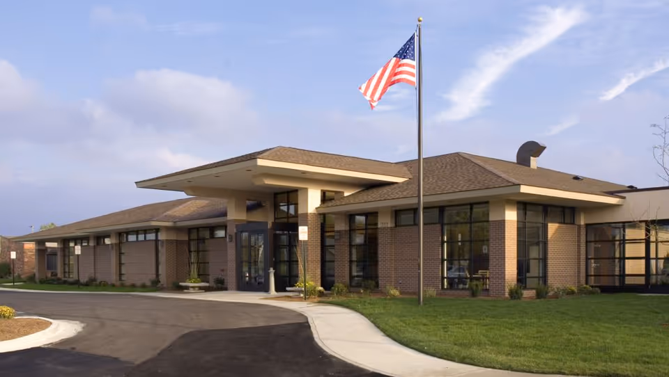 Exterior view of MediLodge of Howell senior living facility with an American flag.
