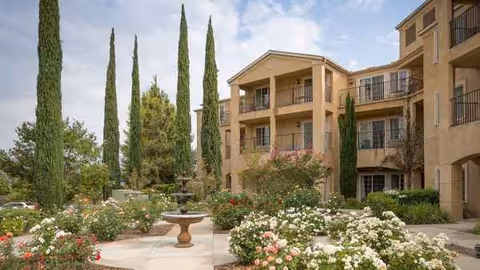 Exterior view of Atria Park of Vintage Hills featuring a courtyard, fountain, and roses.