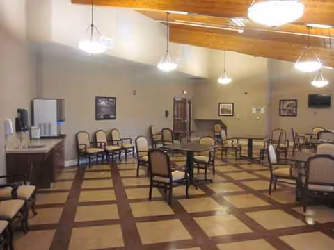 Interior dining room with multiple tables and chairs in a senior living facility.