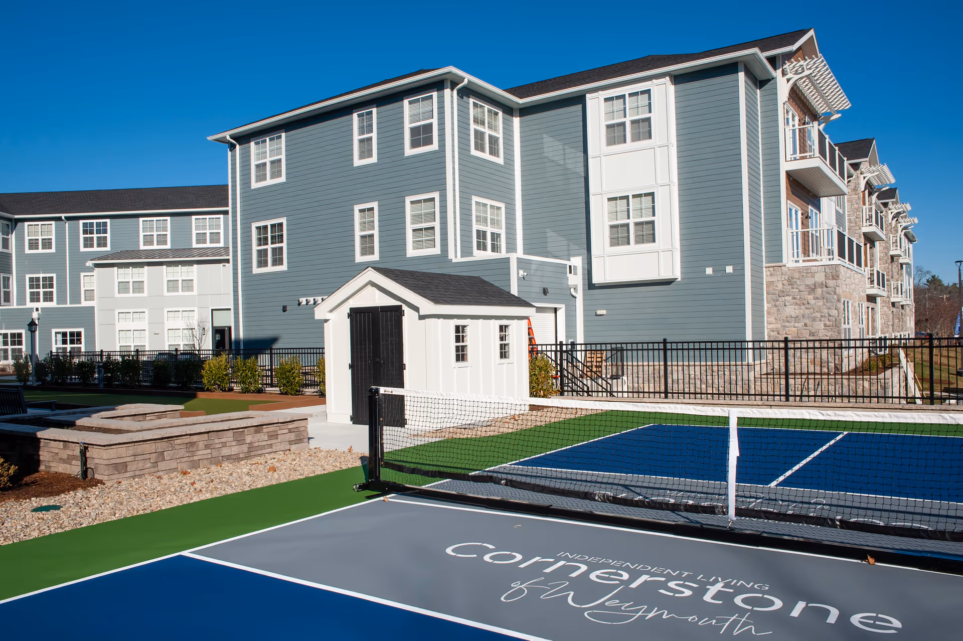 Exterior of Cornerstone of Weymouth showing the building facade, a small white shed, and a pickleball court in the foreground.