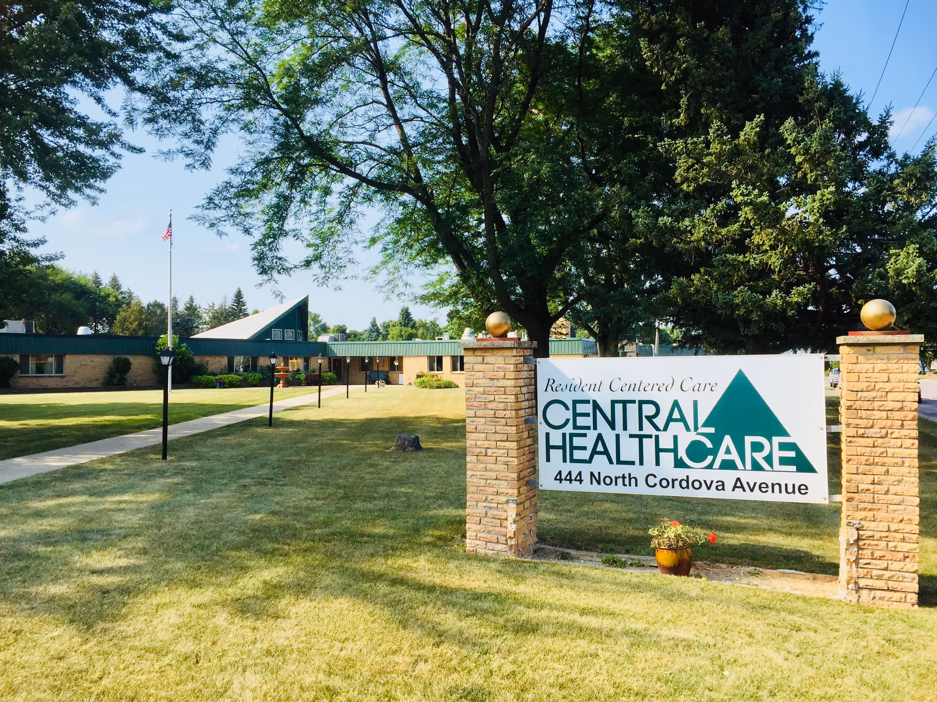 A brick-posted sign reading Central Health Care stands on a grassy front lawn with the single-story facility and trees in the background.
