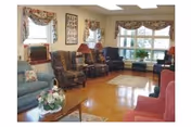 Cozy senior living living room with upholstered chairs, sofas, and large windows.