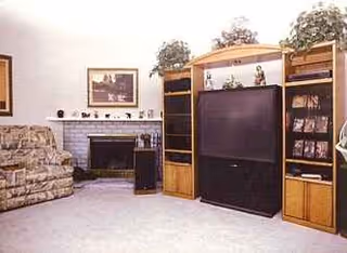 A living room with a floral sofa, fireplace, and a large wooden entertainment center.