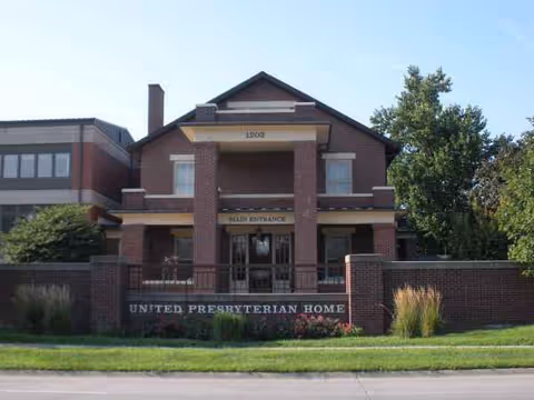 Brick building with pillars and United Presbyterian Home sign at the entrance.