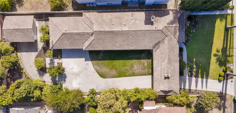 Aerial view of a single-story building with a tiled roof surrounded by greenery, pathways, and landscaped gardens.