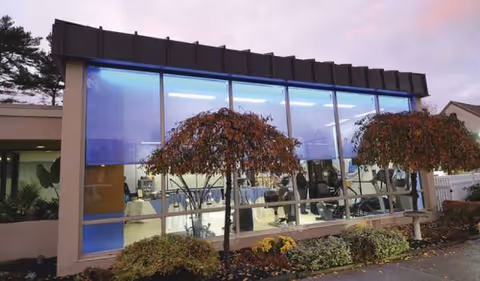 Modern senior living facility with a glass storefront and visible gym equipment inside.