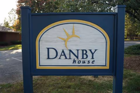 A blue outdoor sign reads Danby House with a sun motif at the entrance.