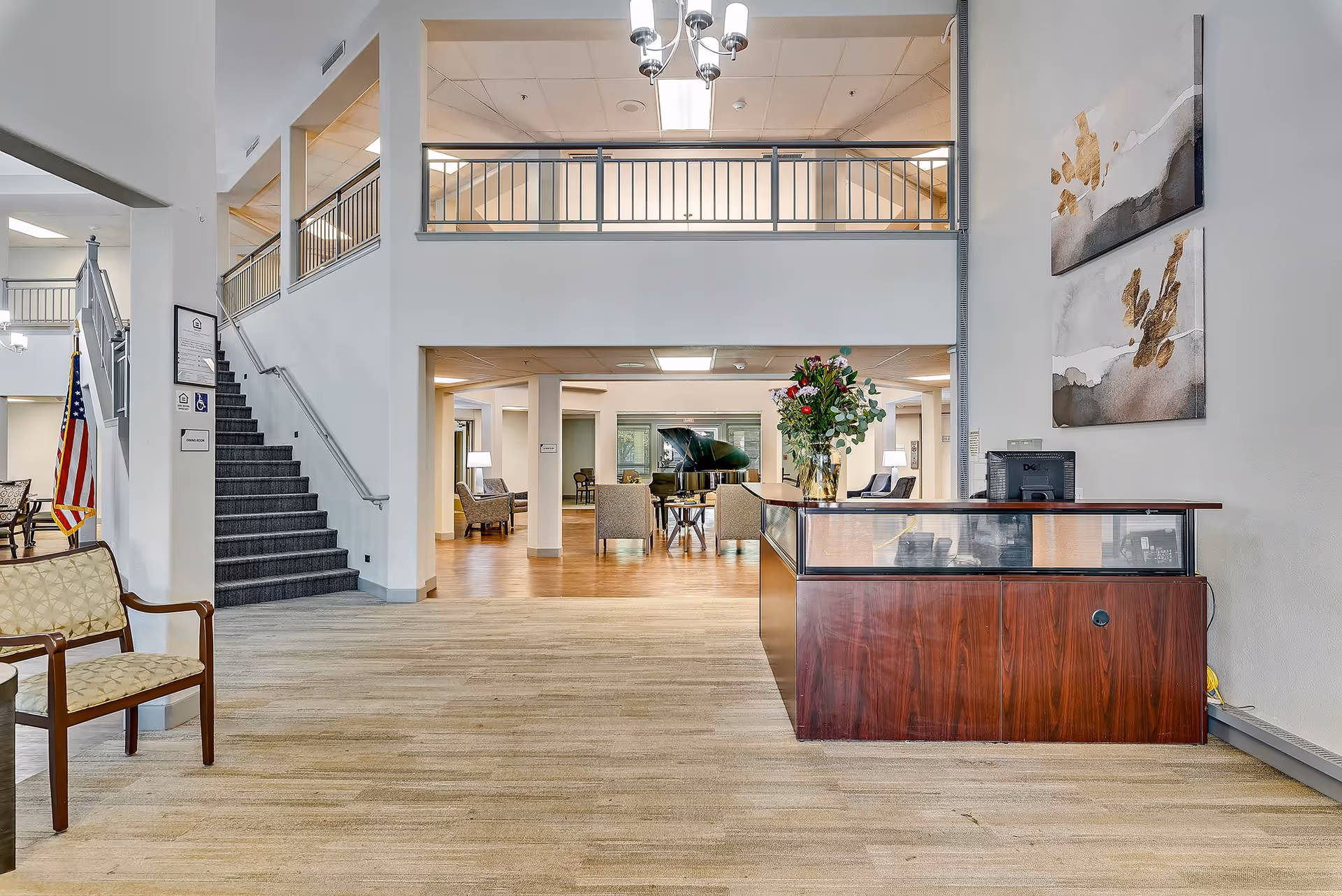 Open two-story reception lobby with a front desk, seating area, staircase, and a grand piano.