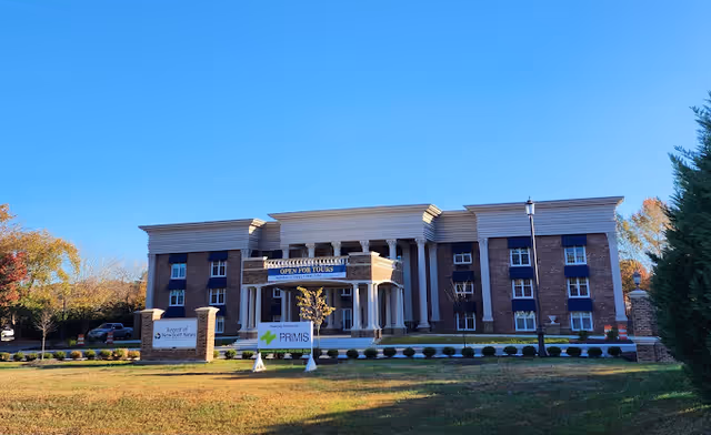 Exterior view of a brick senior living facility with 'Open for Tours' sign at the entrance.