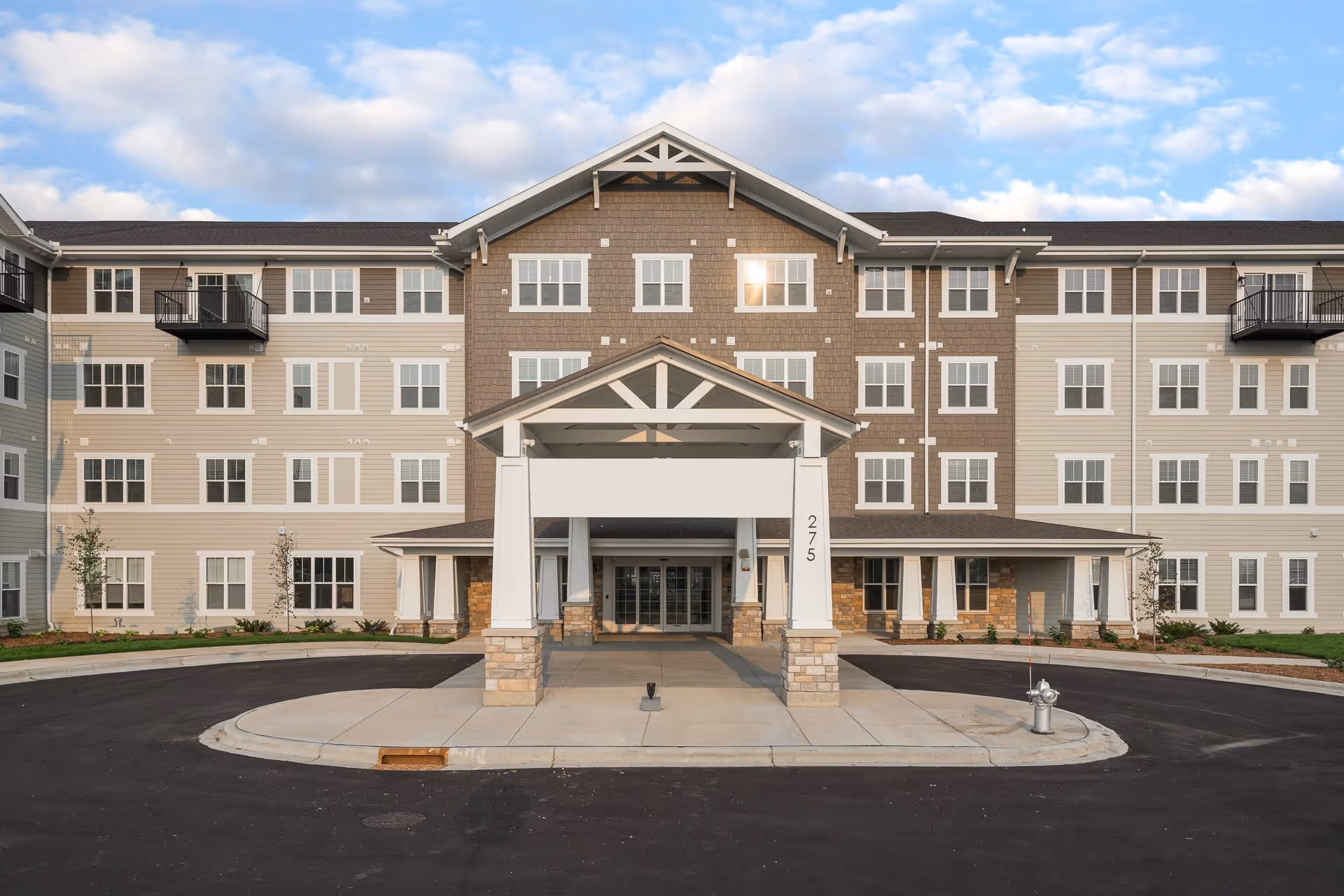 Front facade of a multi-story senior living building with a covered porte-cochere entrance marked "275".