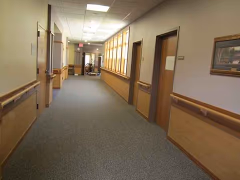 Long interior corridor at Baldwin Care Center with wooden doors along walls.