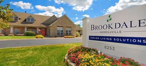 Exterior view of a Brookdale senior living facility with a front sign and landscaped flowers.