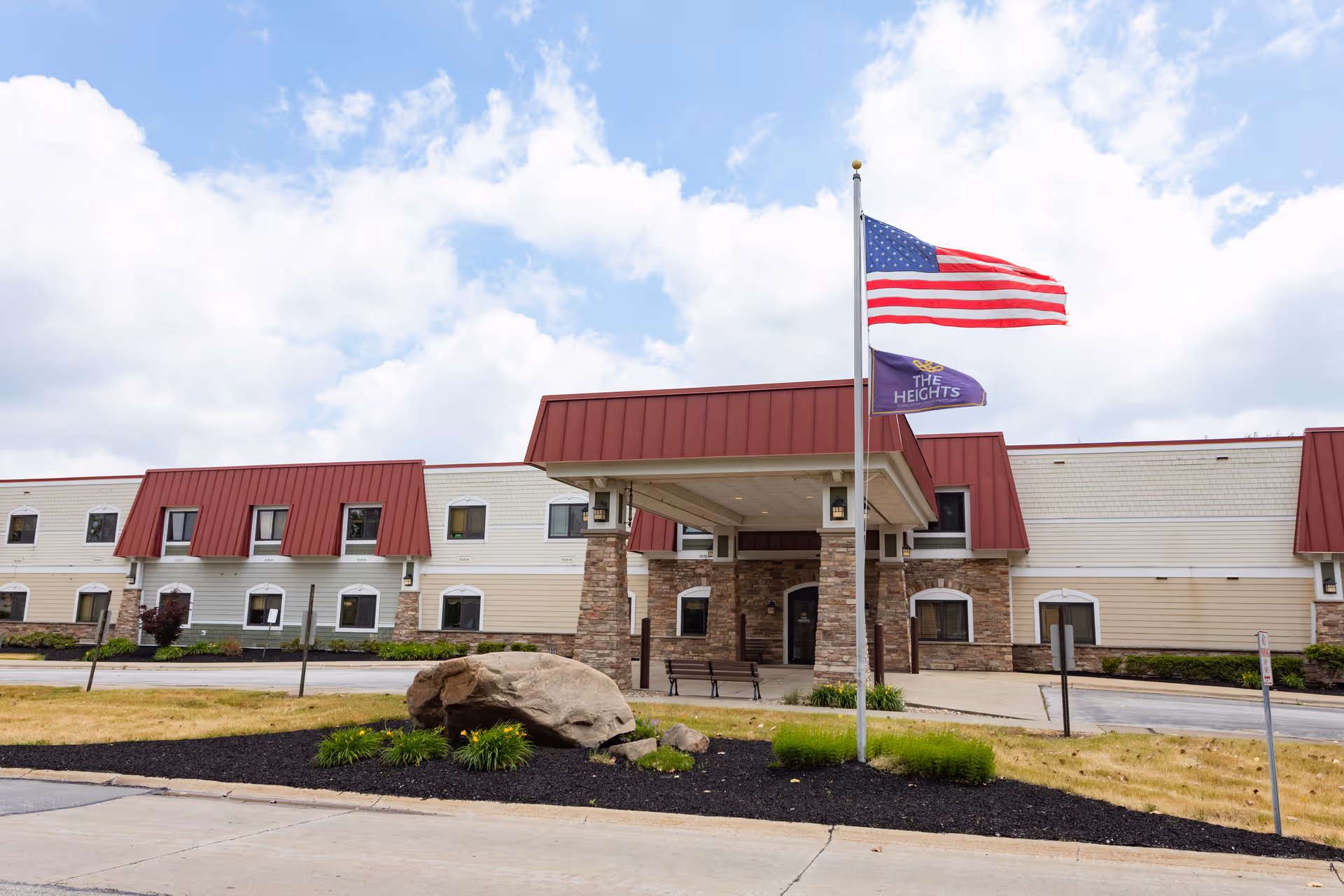 Exterior view of The Heights Rehabilitation and Healthcare Center featuring a flag and entrance.