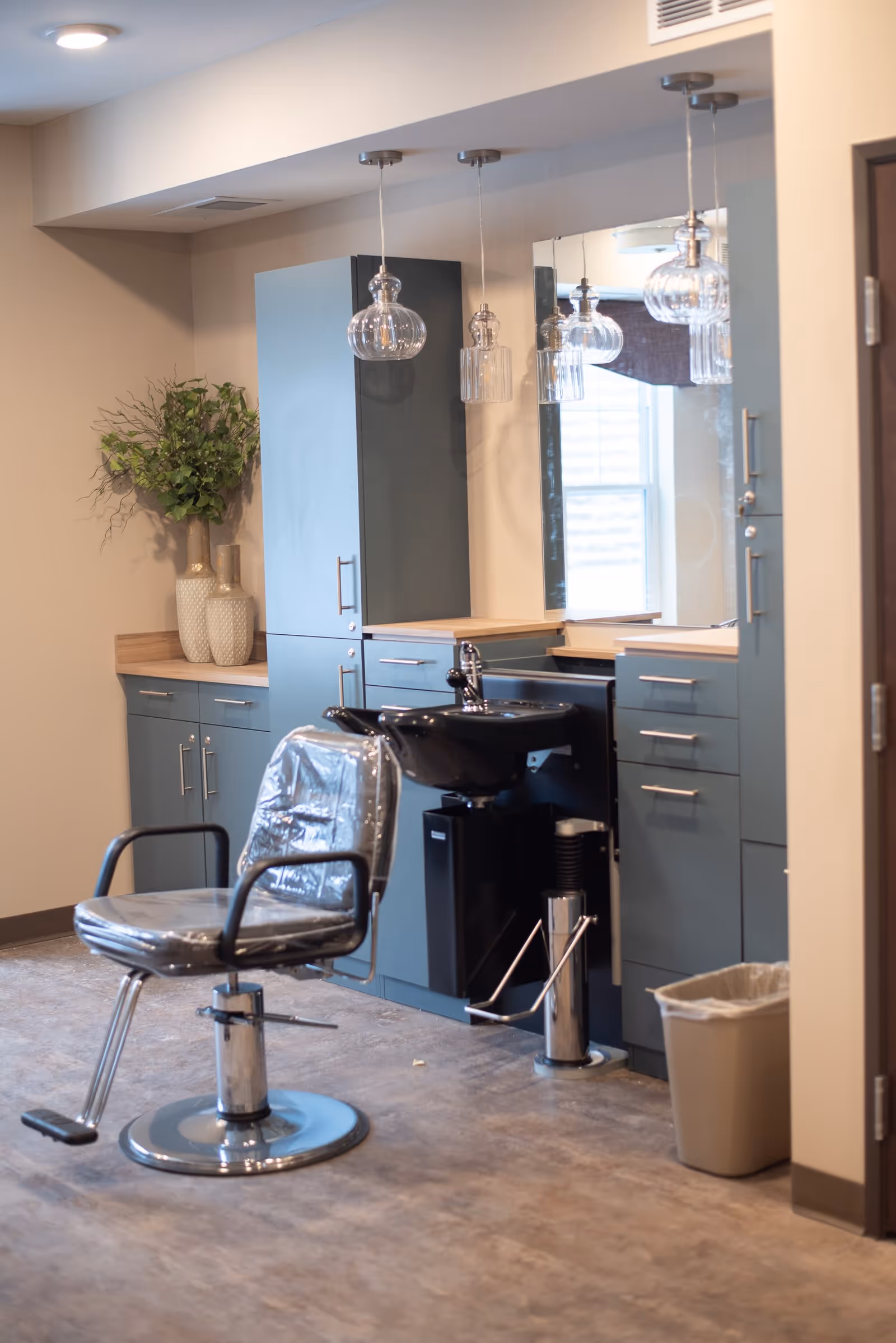 A hair salon station with a styling chair and shampoo sink in front of cabinets and mirrors.