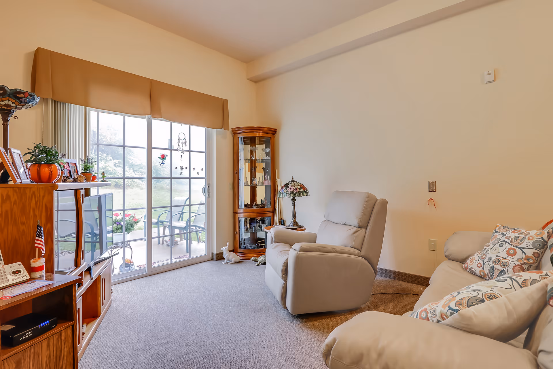 Cozy assisted living living room with a recliner and sofa facing a sliding glass door to a patio.