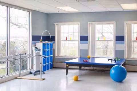 An activity room in a senior living facility featuring a blue table tennis table and equipment.