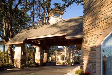 Stone-clad entrance of a senior living facility with a covered porte-cochere.